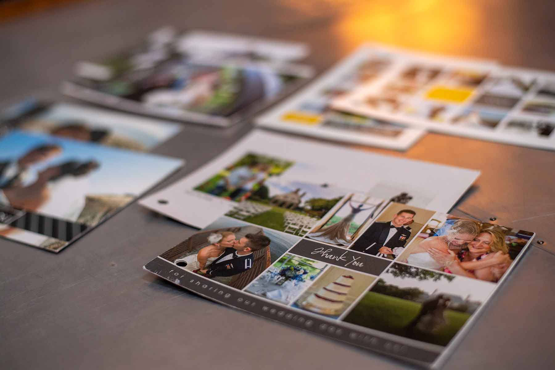 Several wedding photo prints and a thank-you card are spread out on a table, featuring couples and outdoor scenes.