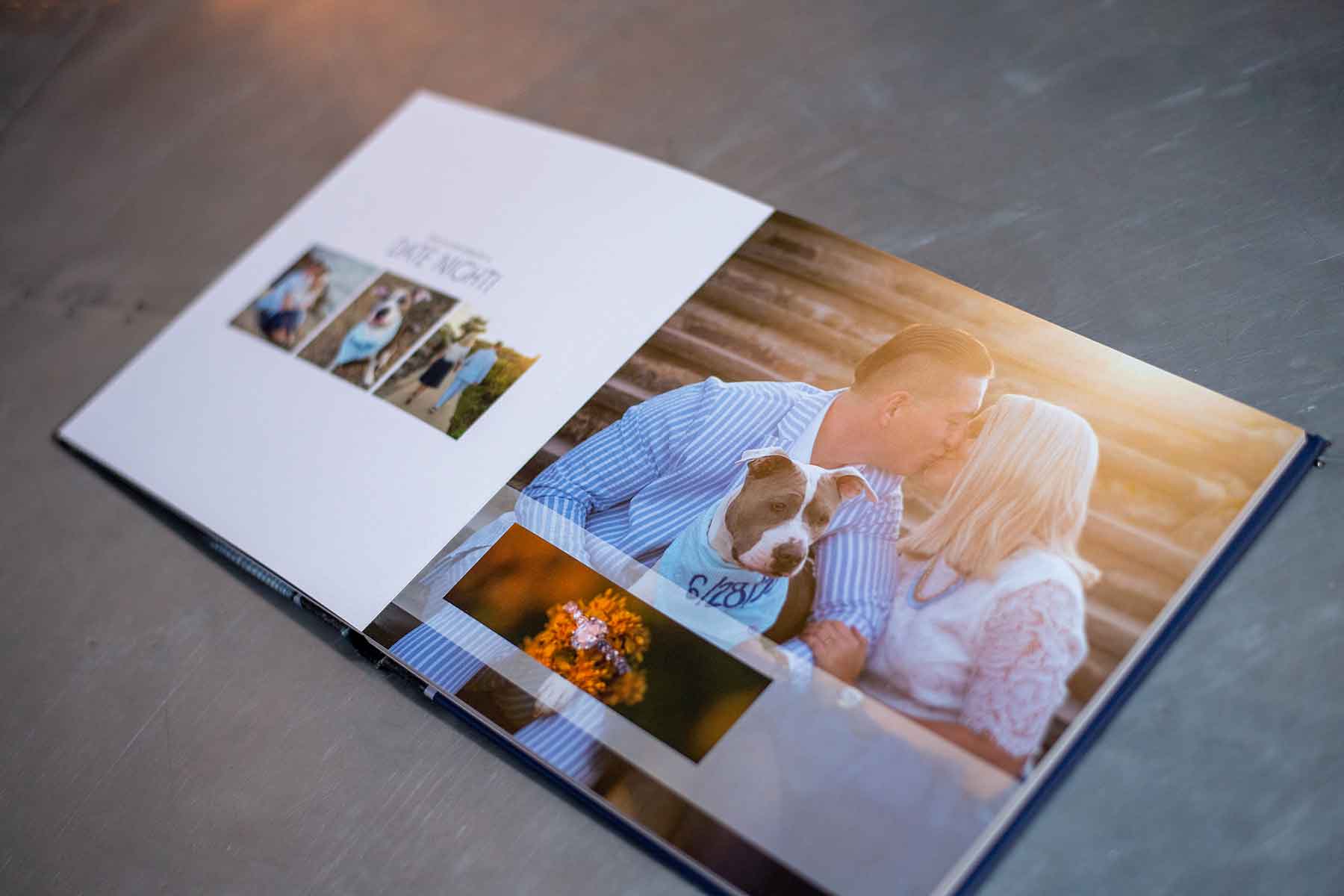 Open photo album showing a couple sitting closely together, kissing, with a dog beside them and a bouquet of flowers in the foreground.