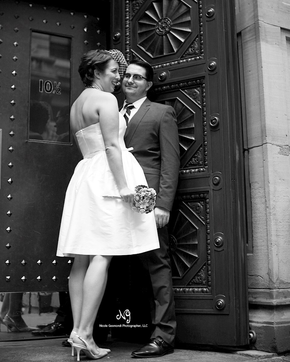 Classic black and white photo of the Bride and Groom in front of the Boston Athenaeum Bride and Groom in front of red doors at Boston Athenaeum