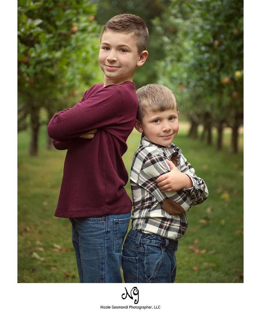 fall family photoshoot at Indian Rock Farm two brothers standing back to back in an apply orchard