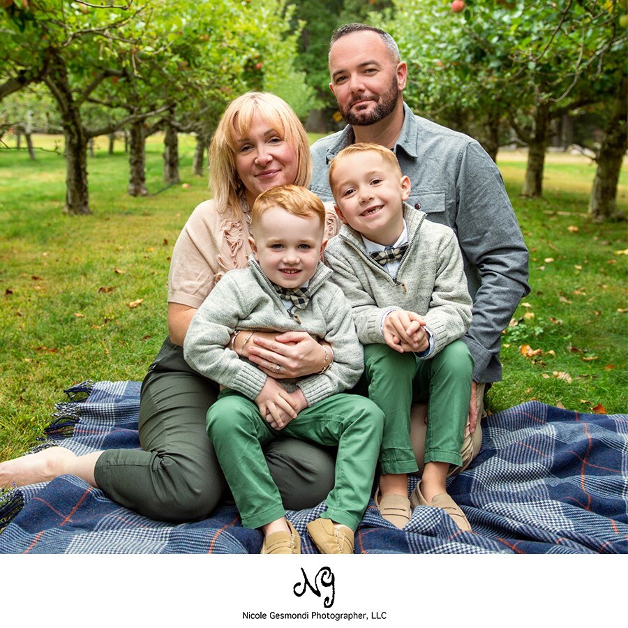 fall family photos family sitting on a blanket at an apple orchard