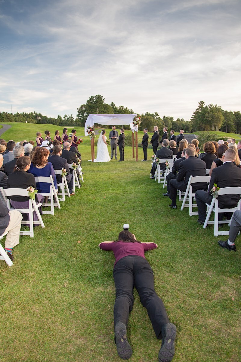 Nicole laying on the lawn to get Ryan and Sarah's wedding ceremony shot Photographer laying down to get the shot
