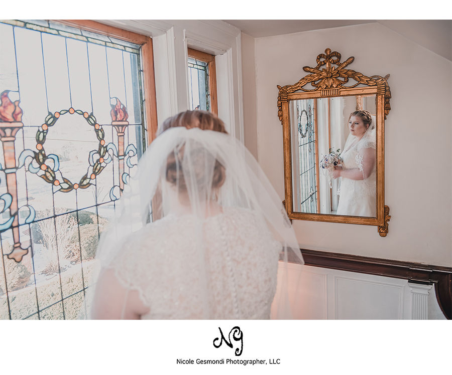 Victorian bride looking in the mirror at her reflection on her wedding day